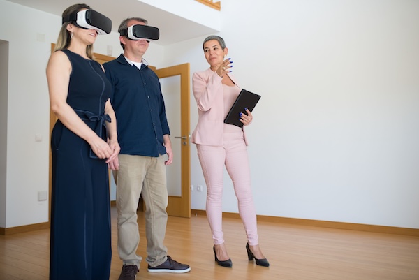 Property Manager giving a tour of a property with two prospective tenants wearing modern virtual reality headsets.